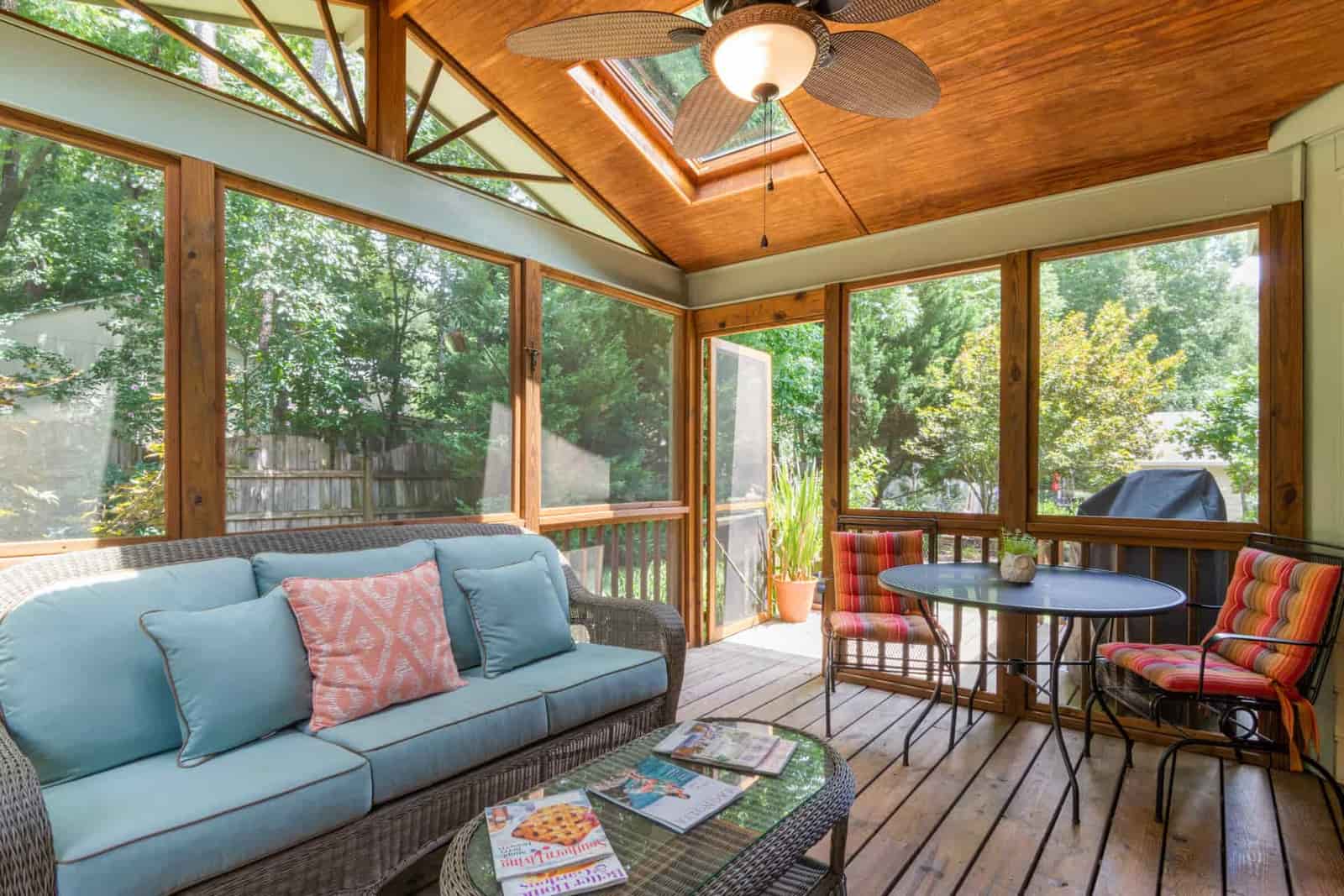 A porch interior with wicker seating and a timber ceiling
