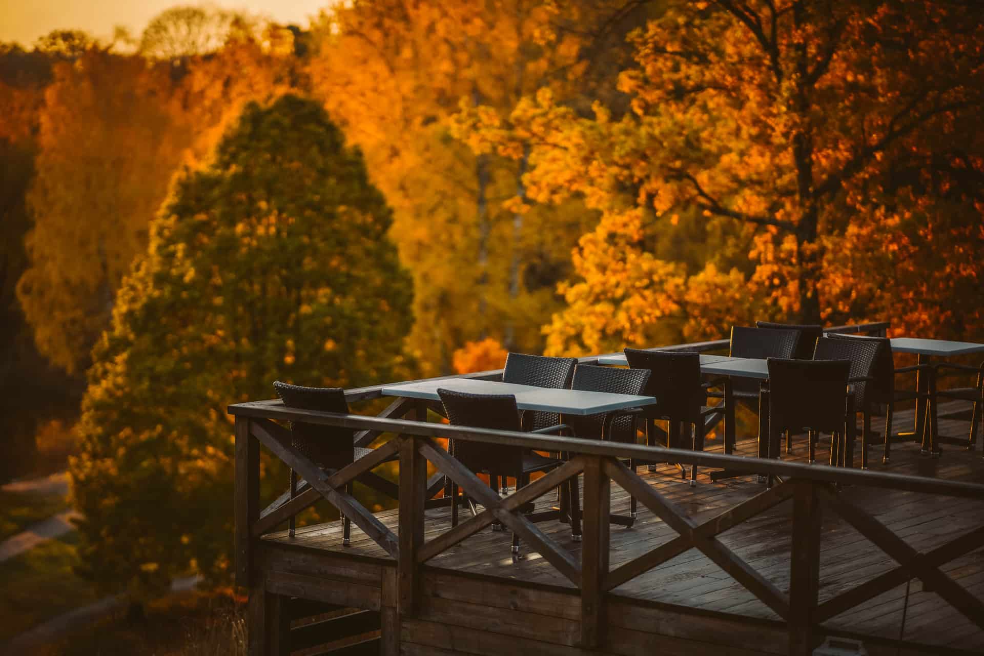 A timber deck with tables and chairs and a railing
