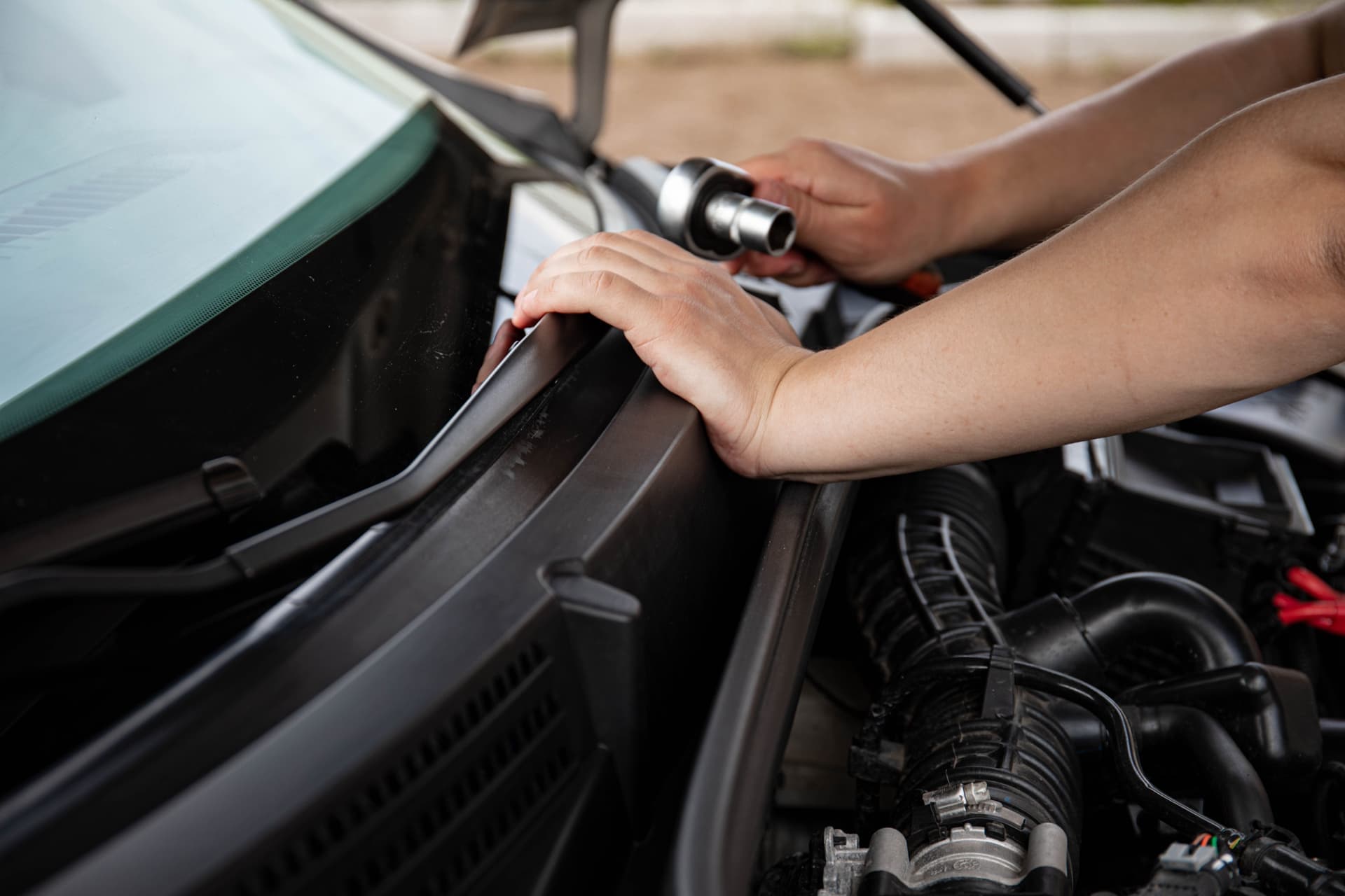 A hand holding a wrench while working on outdoor equipment